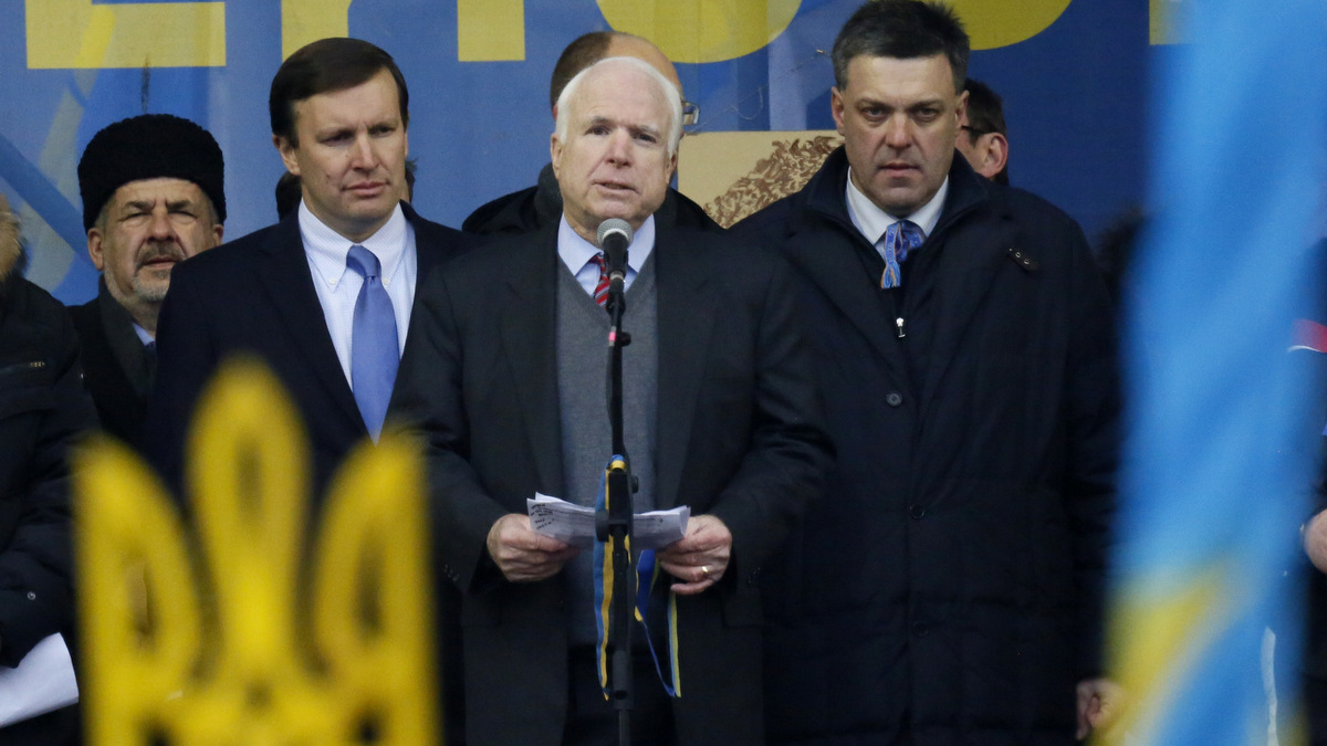 U.S. Senator John McCain, center, speaks as Democratic senator from the state of Connecticut, Chris Murphy, second left, and Opposition leader Oleh Tyahnybok, right, stand around him during a Pro-European Union rally in Independence Square in Kiev, Ukraine, Sunday, Dec. 15, 2013. Ukrainian national symbol is in the foreground. About 200,000 anti-government demonstrators converged on the central square of Ukraine’s capital Sunday, a dramatic demonstration that the opposition’s morale remains strong after nearly four weeks of daily protests. (AP Photo/Dmitry Lovetsky)